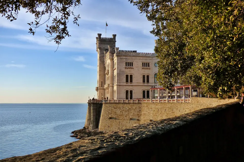 Il Castello di Miramare, bianco, sul promontorio a picco sul mare con il parco alle spalle
