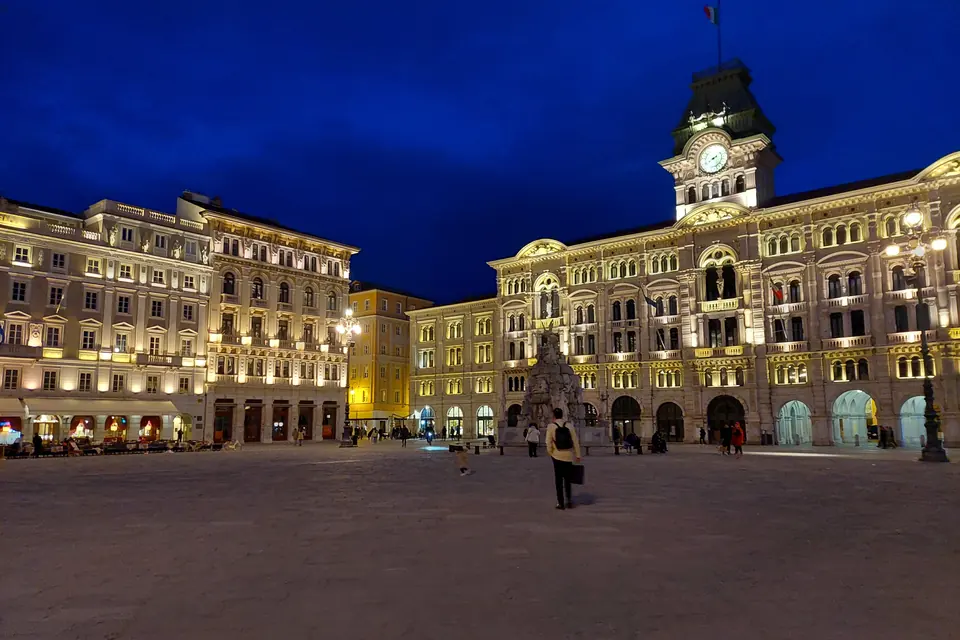 Piazza Unità d’Italia al tramonto, con il Palazzo del Municipio sul fondo e il mare sulla destra