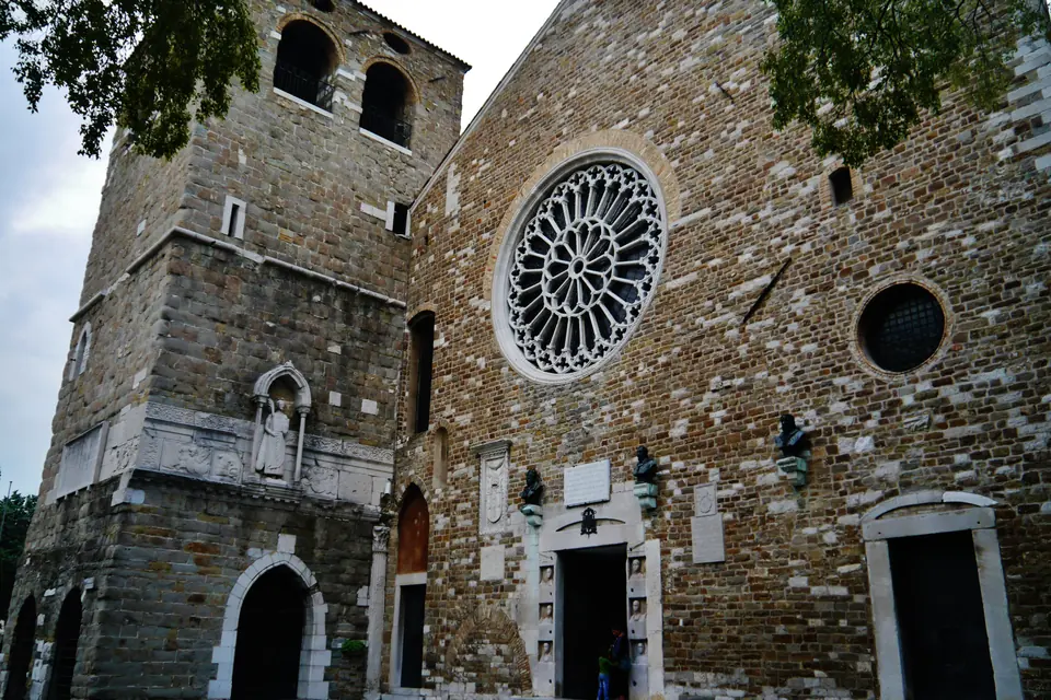 La facciata in pietra della cattedrale di San Giusto con il rosone e il campanile