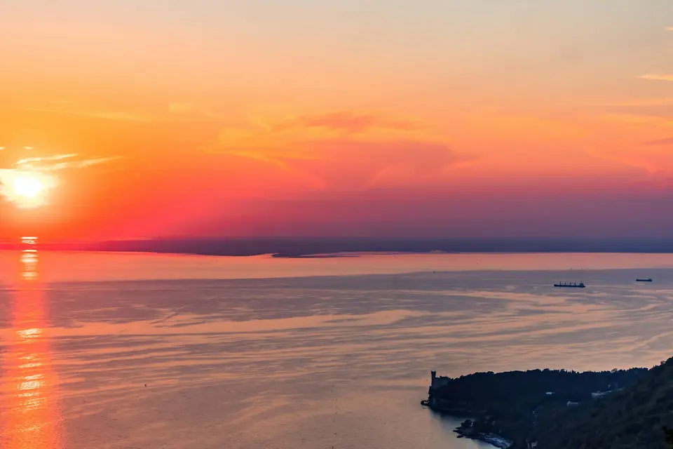 Il sole che tramonta sul golfo di Trieste, con il promontorio in primo piano
